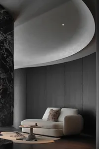 A modern living room featuring fabric seating, concrete columns, and marble accents.