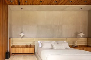 Modern minimalist bedroom with concrete walls and a white bed.