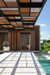 Swimming poolside lounge area with modern wooden and concrete patio furniture, under a wooden slat ceiling.