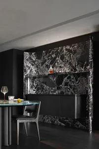 A modern industrial bar counter made of marble with black and white veins, featuring a sleek design with a single chair and a