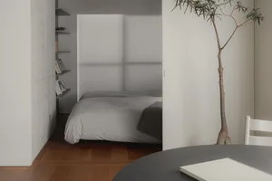 Modern, minimalist bedroom with concrete walls and a bed.