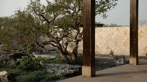 A rock garden with wooden posts and stone walls surrounded by green plants and flowers.