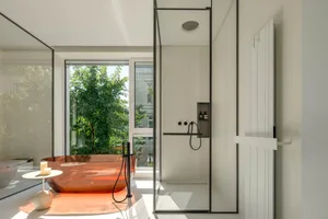 Modern minimalist bathroom featuring a transparent acrylic tub, clear glass shower walls, and concrete flooring.