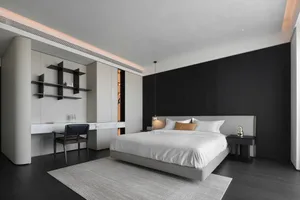 A minimalist bedroom with a bed, side table, and open closet.