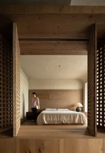 A serene, minimalist bedroom featuring wooden furniture and a neutral color palette.