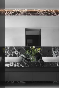 Modern minimalist bathroom with black marble countertops, white sinks, and floral decoration.