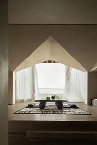 Modern minimalist living space featuring a concrete floor and a large window overlooking a serene landscape.