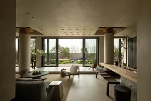 A modern living room with concrete walls and a view of a garden.