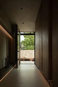 A modern entrance with stone walls and a concrete floor, featuring a window view of greenery.