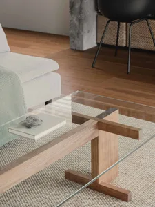 A modern living room with a glass coffee table and wooden accents.