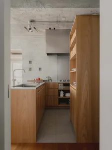 A modern kitchen with wooden cabinets and a concrete ceiling