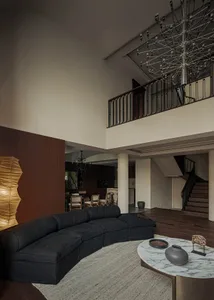Living room with a modern design featuring black furniture and metallic elements, high ceiling, and open layout.
