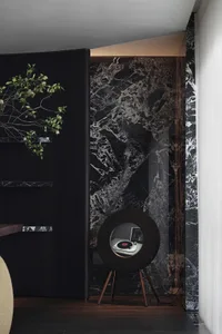A modern living room featuring marble walls and a sleek, round speaker.