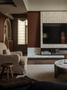 A modern living room featuring a marble fireplace with wood accents and a cozy seating arrangement.