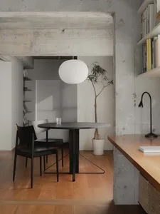 Photograph of a modern, minimalist interior with concrete walls, wooden furniture, and a round table with chairs.
