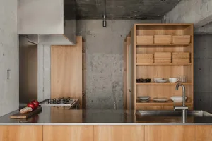 Modern minimalist residential kitchen with concrete hexagonal patterned backsplash, wooden cabinetry, and stainless steel app