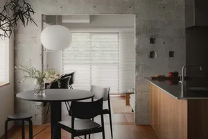 A modern kitchen with a pillar, concrete walls, and a round dining table.