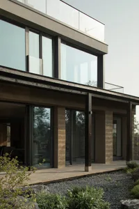 Modern residential exterior and entrance showcasing concrete walls and large glass windows.