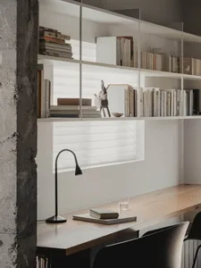 A minimalist office space with a wooden desk, bookshelf, and lamp, featuring a white background and books.