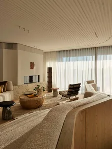 A minimalist living room with wooden furniture, fabric accents, and glass elements.
