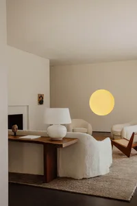 A minimalist living room features wooden furniture, fabric upholstery, and a glass wall or window.