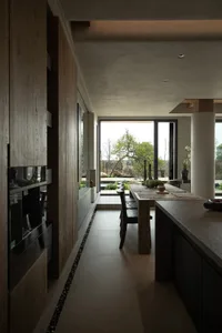 A minimalist residential kitchen with wood, stone, and concrete materials.
