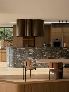 Minimalist residential kitchen featuring a marble backsplash and wooden elements.