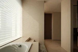 A minimalist modern bathroom with a scene of sunlight shining through the window, creating patterns on the walls and floor, f