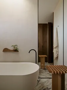 A modern bathroom with marble walls and floor, featuring a freestanding bathtub and minimalist design elements.