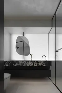 Modern minimalist bathroom with marble elements and a unique mirror hanging in front of the window.