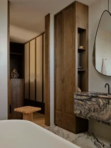 Modern bathroom with wooden cabinets and marble countertop, featuring a minimalist design.