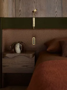 A bedroom with modern decor, featuring a bed and nightstand with wood-texture accents.