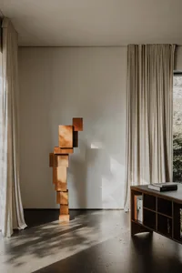 A modern interior living space featuring corten steel art sculpture and natural light.