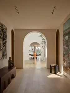 A modern interior with light timber flooring, white walls, and arched doorways.