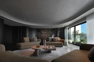 Contemporary living room with fabric furniture, stone coffee tables, and metal accents.