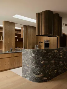 Modern residential kitchen with marble countertops and wooden cabinets.