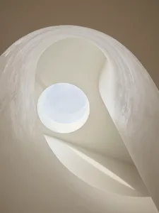 Circular staircase with concrete walls and a circular skylight.