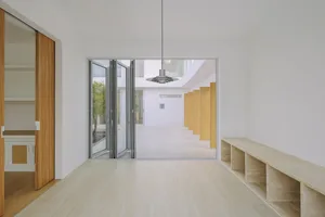 Modern minimalist interior space with glass walls, concrete floors, and wooden bench seating.