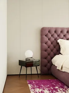 A modern minimalist bedroom featuring a purple tufted upholstered headboard and a sleek black side table with a white spheric