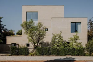 Modern architectural house facade featuring minimalistic design with large rectangular windows and a textured sandstone exter