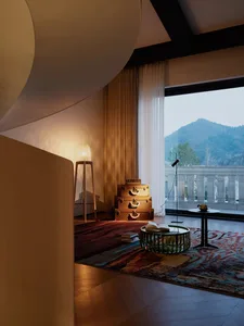 A modern living room featuring wood and concrete materials, with a floor lamp, stacked luggage, and a coffee table.