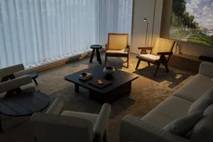 Modern minimalist living room with wooden furniture, a large window with sheer curtains, and a wall-mounted lamp.