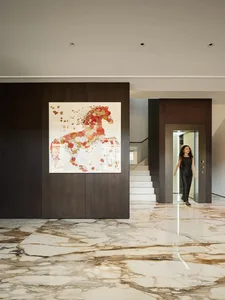 An entryway featuring a modern marble floor with a large, colorful abstract horse artwork on the wall.