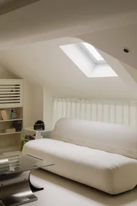 Modern minimalist living room with white sofa, glass coffee table, and skylight.