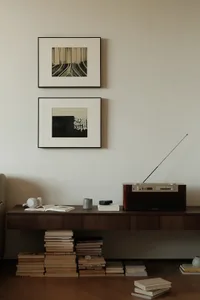A minimalist living room storage unit with a radio, framed art, and stacked books.
