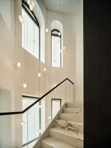 Modern staircase with white marble steps and black metal railings.