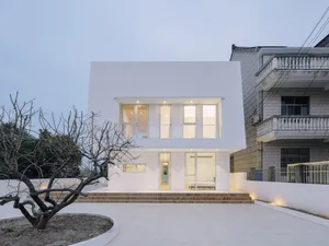 Two-story modern residential building with white exterior and concrete steps.