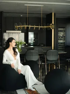 A minimalist interior design featuring black and white decor with a woman in a white dress sitting on a black spherical chair
