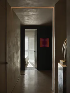 A glimpse into a minimalist interior design space featuring a concrete floor and a modern artwork on a black wall.