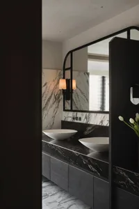 A modern bathroom with marble walls and floors, featuring sleek white sinks.